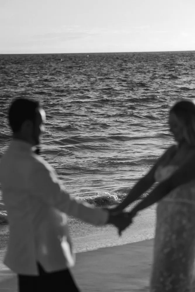 Black and white silhouette of two figures holding hands by the sea